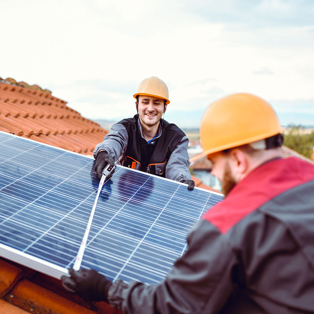 Zwei Männer arbeiten auf einem Dach an einer Solaranlage