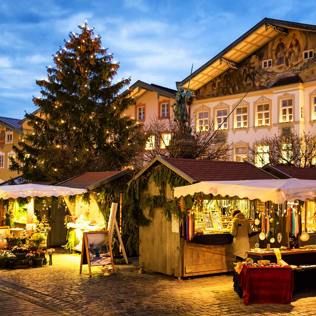 Verschiedene beleuchtete Stände auf einem Weihnachtsmarkt am Abend