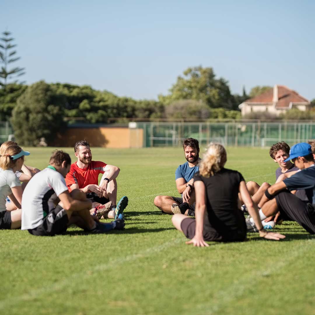 Fußballmanschaft sitzt gemeinsam auf einem Rasen