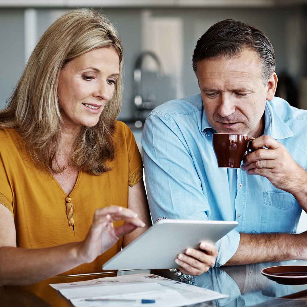 Ein Ehepaar mittleren Alters betrachtet gemeinsam ein Tablet